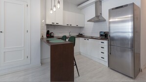 A modern kitchen with white cabinets, a stainless steel refrigerator, and pendant lights. - Jinetes Holidays in M Laga (Málaga)