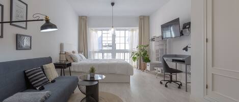 Un dormitorio moderno con cama, escritorio y sofá.