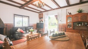 A cozy living room with a wooden dining table, a leather sofa, and a television. - La Morada Del Yayo in Guillena (Guillena)
