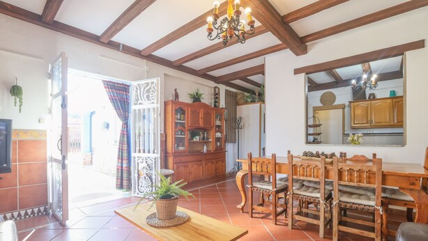 A spacious living room with a wooden dining table, chairs, and a chandelier. - La Morada Del Yayo in Guillena (Guillena)