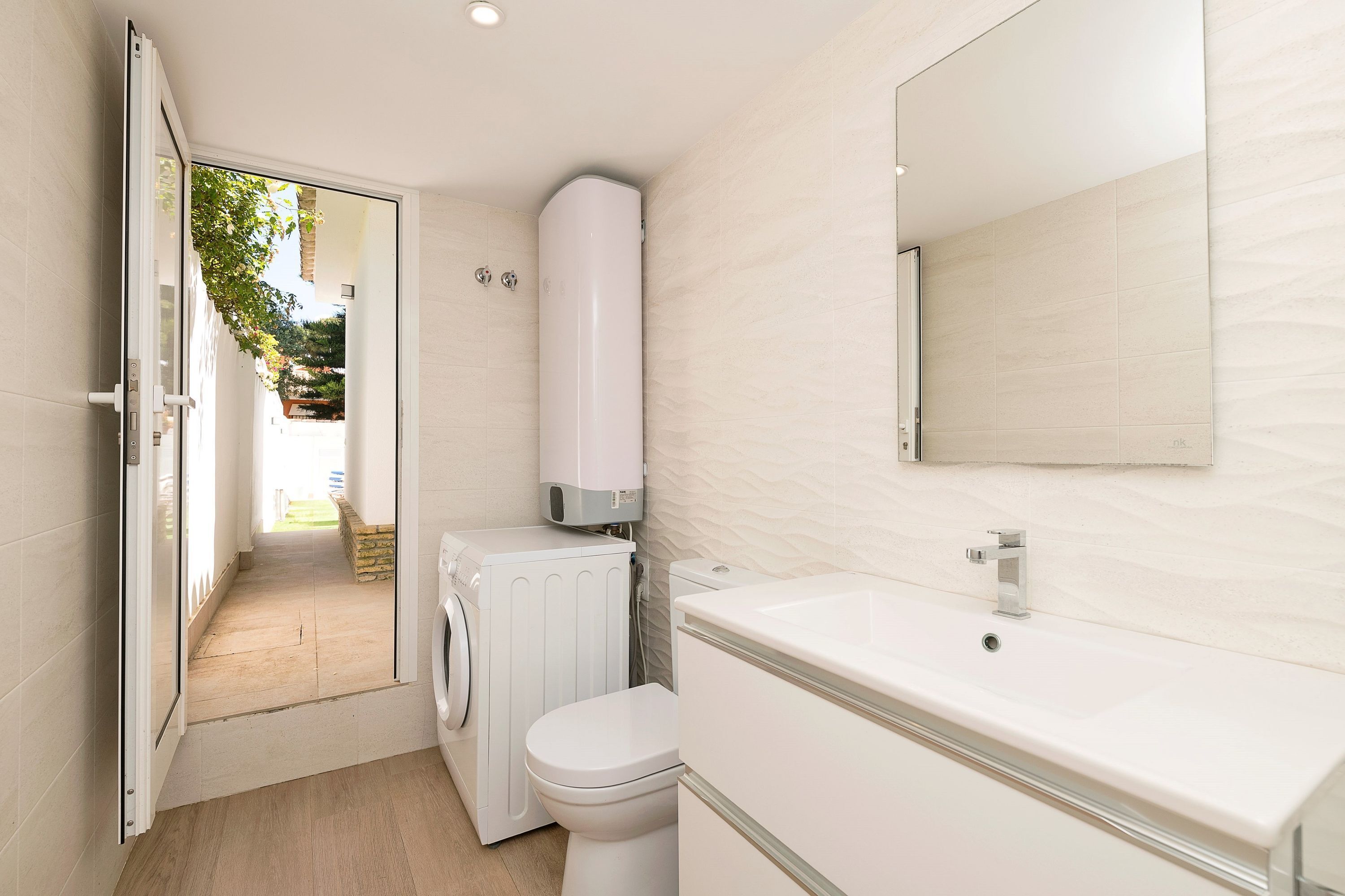 A modern bathroom with a toilet, washing machine, and sink.
