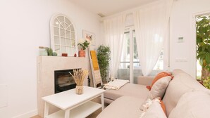 A modern living room with a fireplace, a sofa, a coffee table, and a large window with sheer curtains.