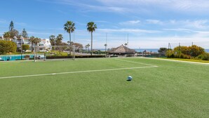 Un campo da calcio con un palo della porta, palme e un edificio sullo sfondo.