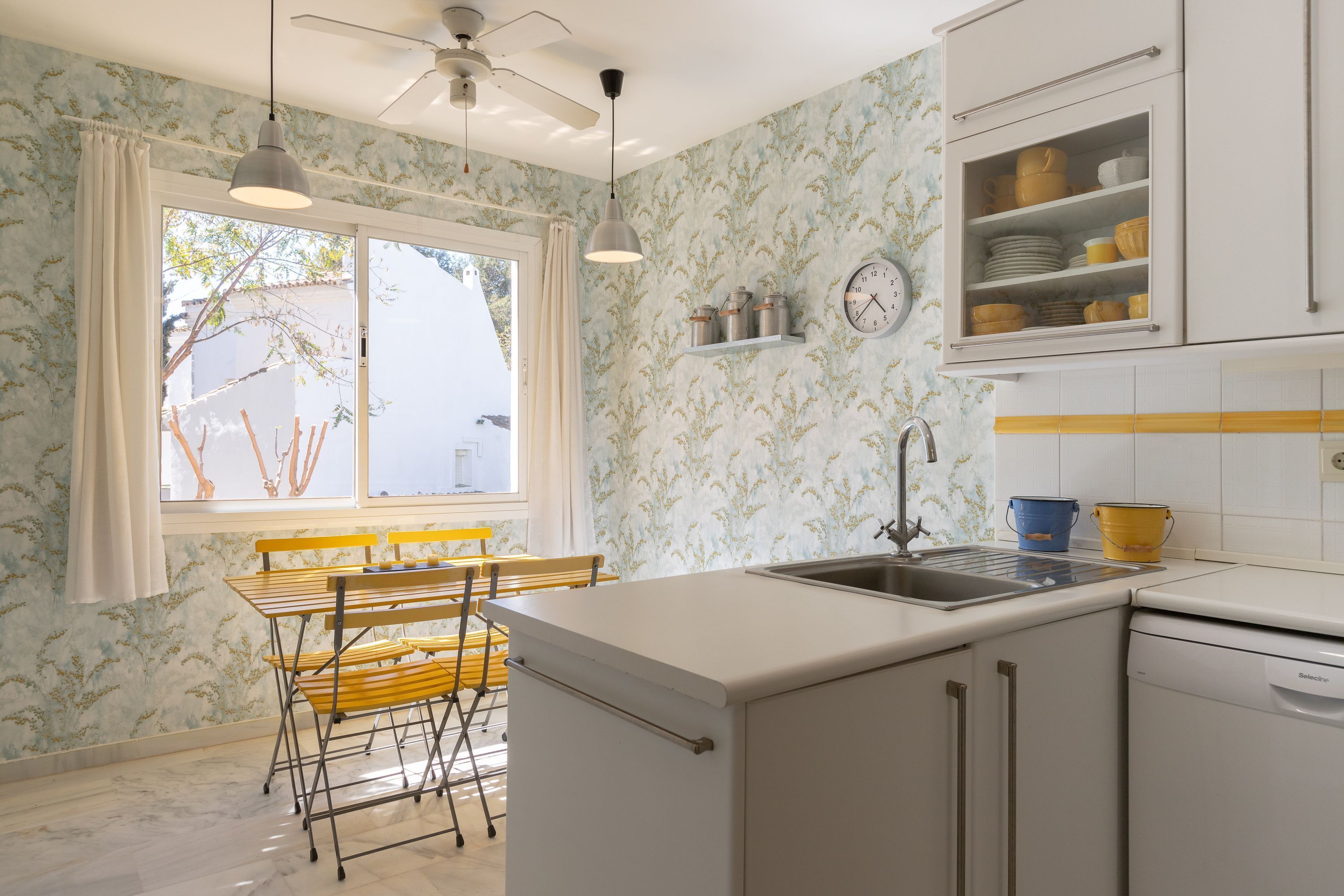 A kitchen with a window, a sink, and a dining area with a table and chairs.