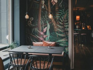 Comedor con mesa, sillas y un mural que representa un paisaje forestal.