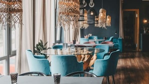 A modern interior with a round glass table, blue chairs, and hanging light fixtures. - 4 Star Holiday Home in Hisings Backa (Hisings Backa)