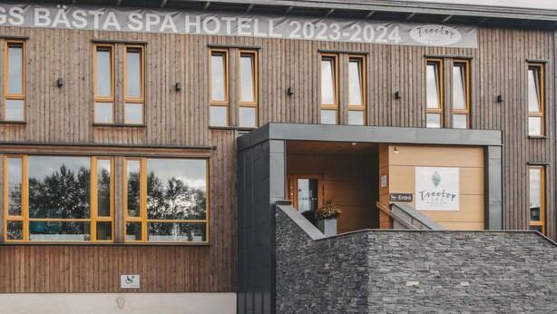 A spa hotel with a wooden facade, a stone entrance, and a sign indicating the name and years 2023-2024. - 4 Star Holiday Home in Hisings Backa (Hisings Backa)