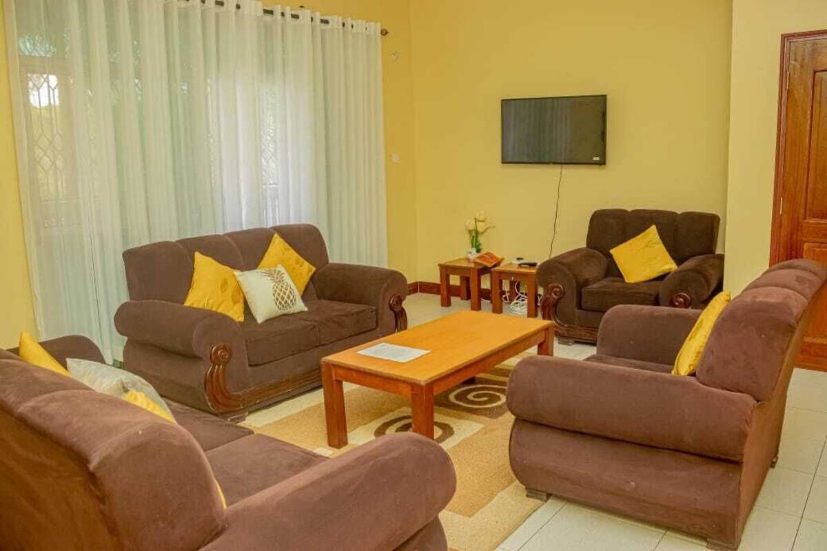 Sala de estar com sofás marrons, mesa de centro de madeira e televisão na parede.