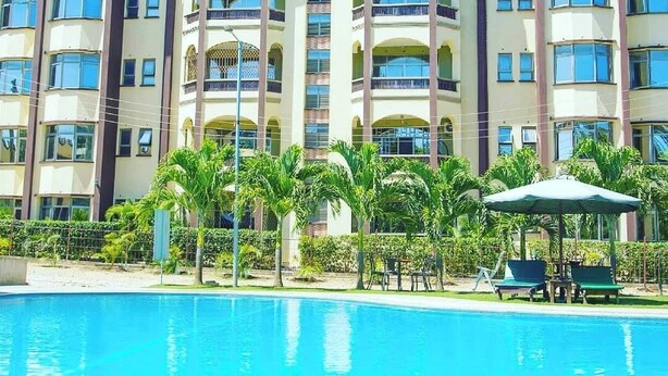 Un hotel a più piani con balconi, una piscina e palme.