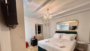 Habitación de hotel con una cama grande, un candelabro, un espejo y un armario.
