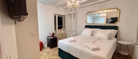 Une chambre d’hôtel avec un grand lit, un lustre, un miroir et une armoire.