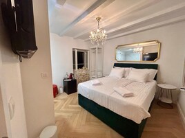 Quarto de hotel com cama grande, lustre, espelho e guarda-roupa.