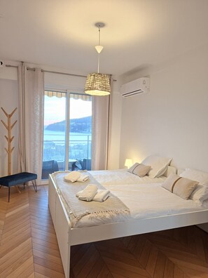 Une chambre avec un grand lit, une vue sur l’extérieur et un ventilateur de plafond.