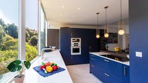 Cozinha moderna com uma janela grande, forno embutido e um armário azul.