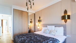 Quarto moderno com cama grande, espelho e luminárias fixadas na parede.