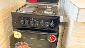 A black stove with a 5-year warranty sticker, a brand logo, and a cooking image sticker. - Munyonyo 2bedroom Joy Apartments (Kampala)