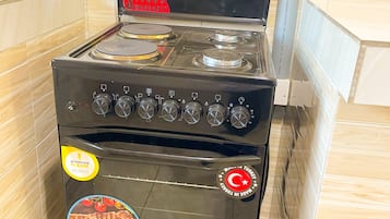 A black stove with a 5-year warranty sticker, a brand logo, and a cooking image sticker.