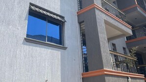 A multi-story building with balconies, large windows, and a textured facade. - Munyonyo 2bedroom Joy Apartments (Kampala)