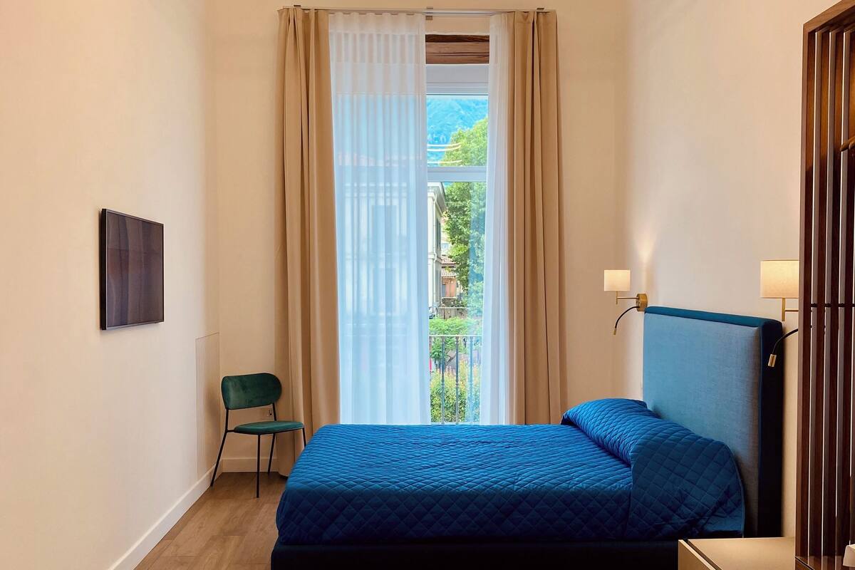Een moderne slaapkamer met een bed, een stoel, een tafeltje en een nachtkastje.