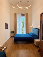 Un dormitorio moderno con una cama, una silla, una mesita y una mesita de noche.