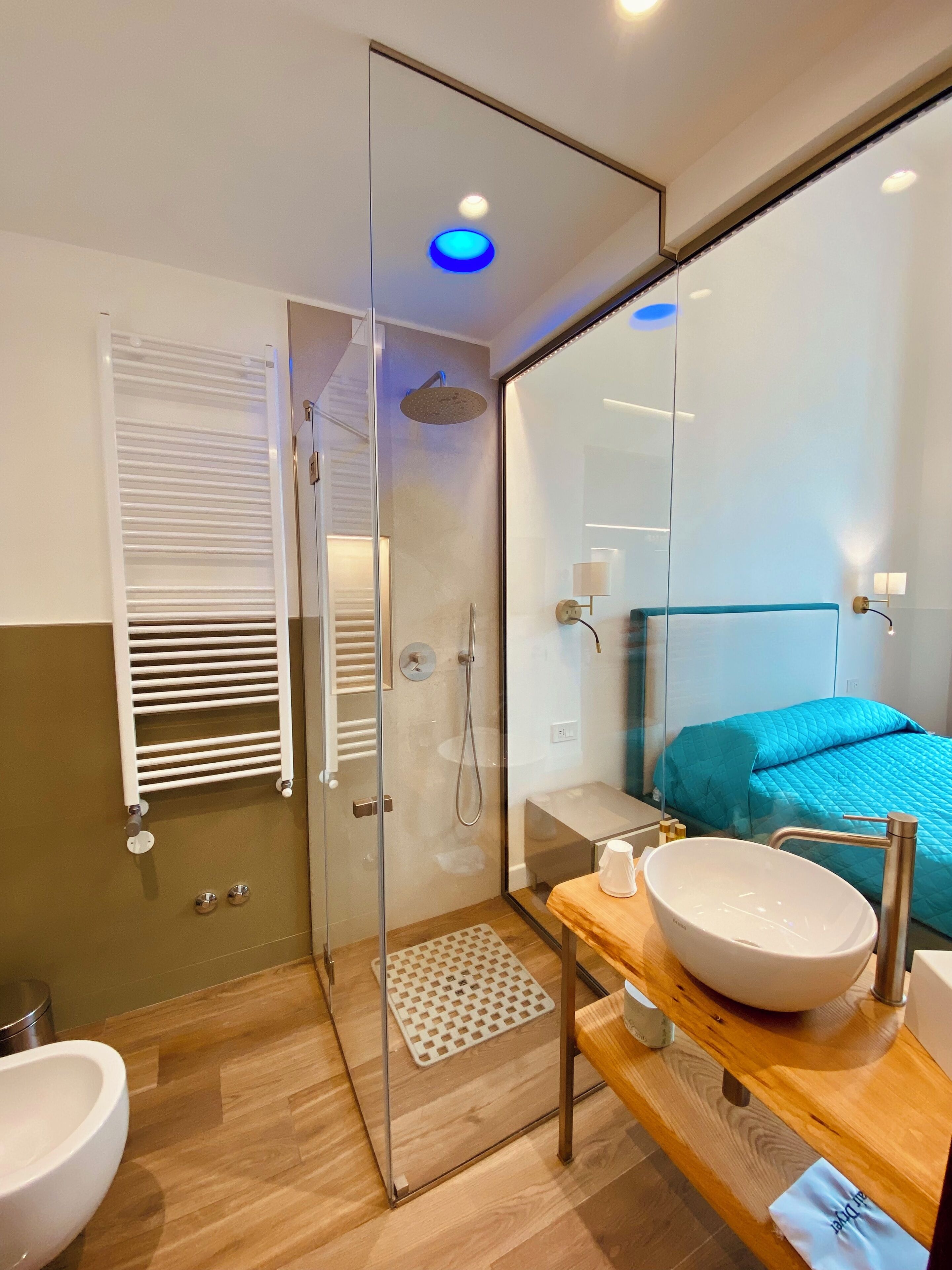 A modern bathroom with a glass shower enclosure, a white sink, and a wooden vanity.