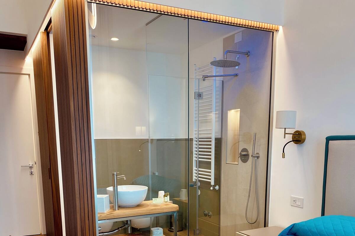 Een moderne slaapkamer met een groot bed, een douchecabine van glas en een houten garderobe.