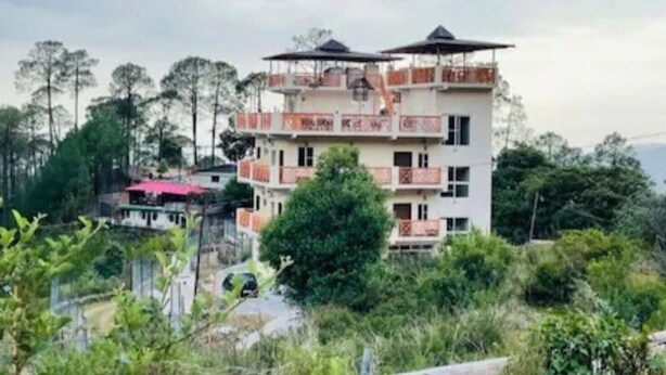 Un edificio a più piani con balconi, immerso nel verde e alberi.