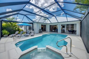 A swimming pool with a glass ceiling, surrounded by lounge chairs and a patio area.