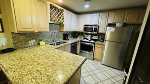 Una cocina con encimeras de granito, electrodomésticos de acero inoxidable y armarios de tonos claros.