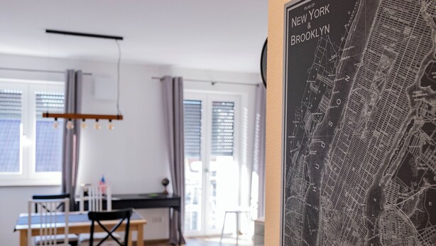 A modern living space with a dining area, a large map of New York, Brooklyn, and a view of the city through the window. - Apartment New York (Forheim)