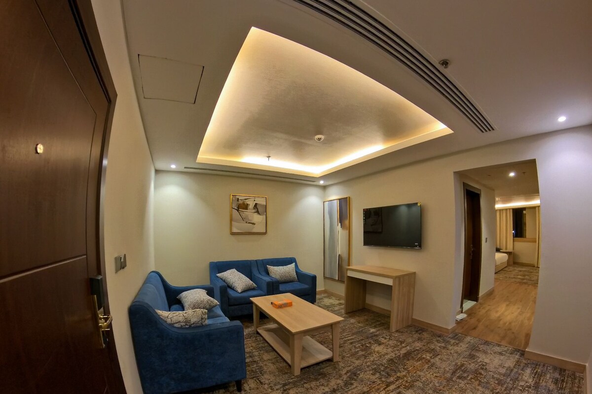 A modern living room with a sofa set, a coffee table, and a flat-screen TV mounted on the wall.