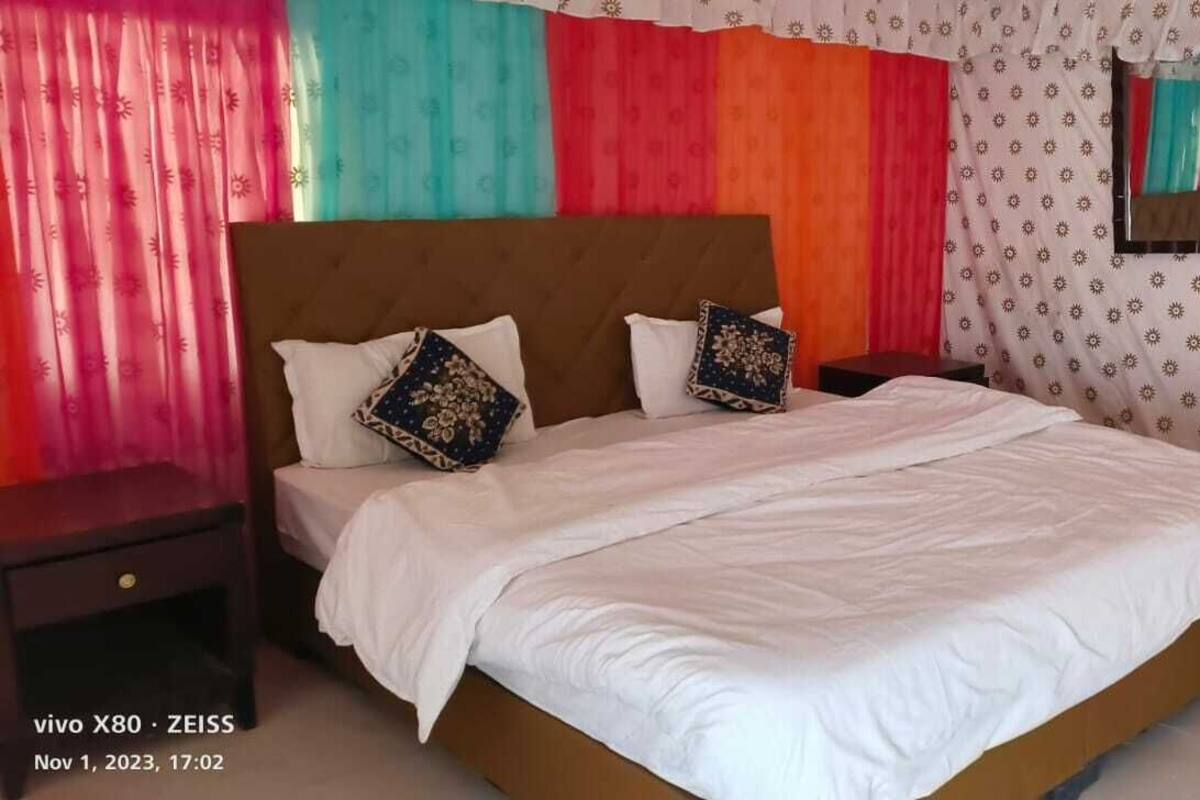A double bed with white bedding, two decorative pillows, and a wooden headboard.