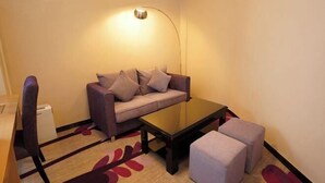 A compact living space with a sofa, ottoman, coffee table, and a lamp. - Lavande Hotel (Qingyuan City Square Feilai Lake Branch) (Qingyuan)