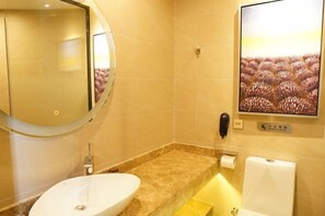 A bathroom with a round mirror, a sink, a toilet, and a towel rack.