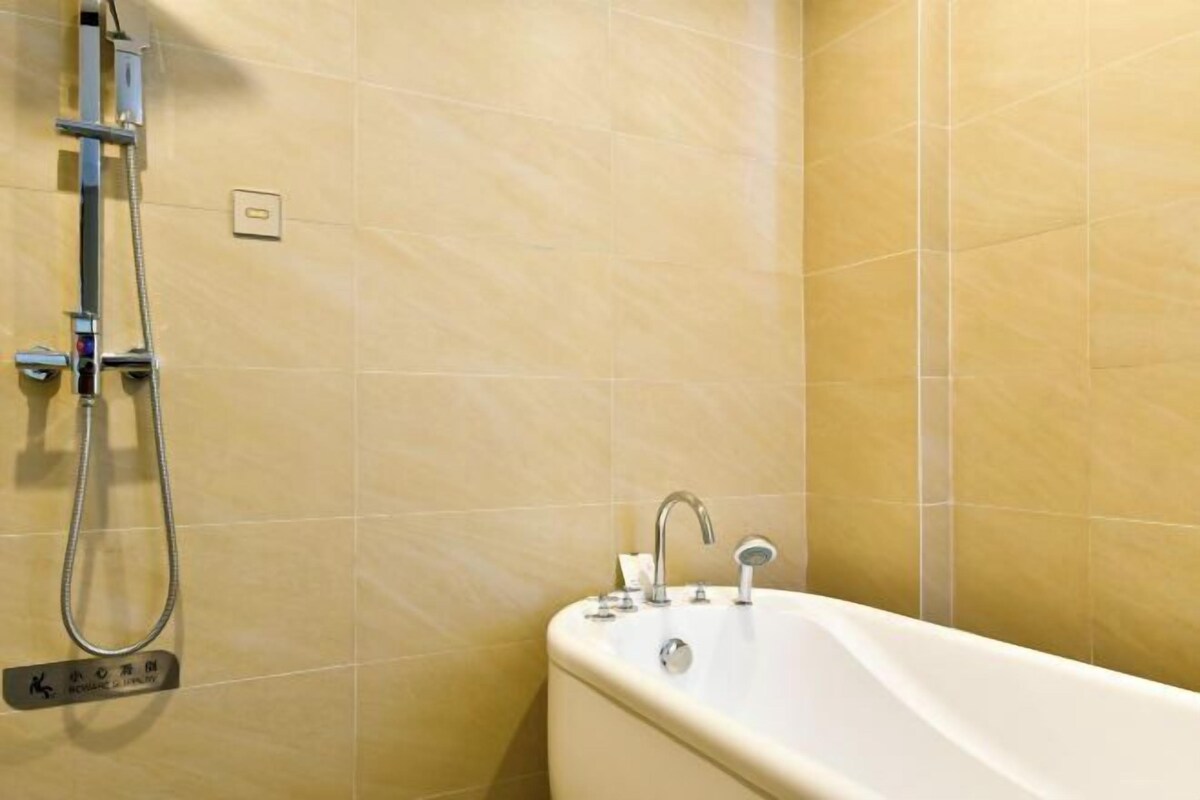 A bathroom with a bathtub, a showerhead, and a control panel.