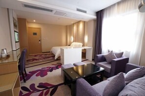 A hotel room with a bed, a desk, a sofa, and a coffee table.