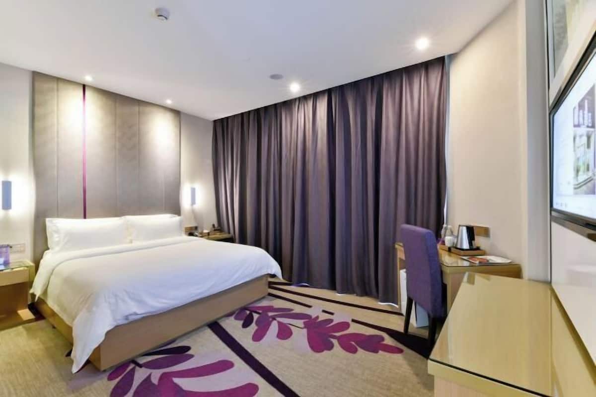 A modern hotel room with a large bed, a desk, and a chair.