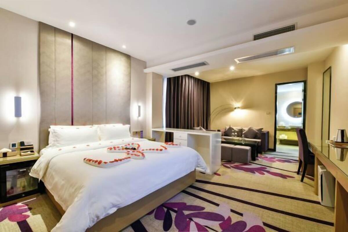 A modern hotel room with a large bed, a desk, and a seating area.