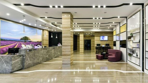 A modern hotel lobby with a reception desk, seating area, and a large painting of a landscape. - Lavande Hotel (Qingyuan City Square Feilai Lake Branch) (Qingyuan)