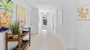 A hallway with a bench, a potted plant, and framed artwork on the walls.