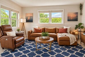 A living room with a brown leather sofa, a brown leather armchair, a round coffee table, and a patterned rug.