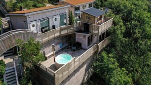 Et flerplans træhus med pool på taget, omgivet af tæt skov.