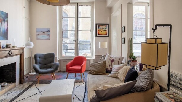 A living room with a fireplace, a sofa, a red chair, and a lamp.