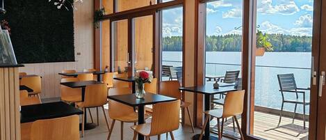 Ein modernes Interieur mit Holzboden und -decke, großen Fenstern und Seeblick.