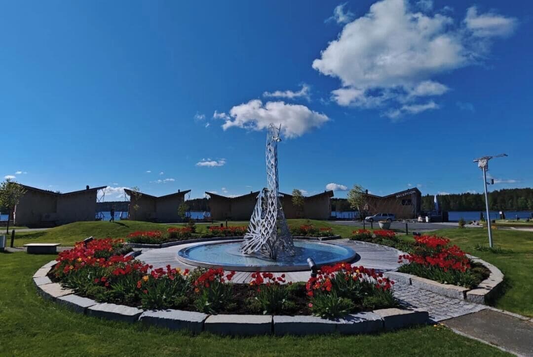 Une cour intérieure avec une fontaine centrale, entourée de parterres de fleurs et de bâtiments.