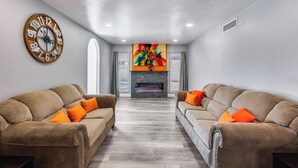 A modern living room with two sofas, a fireplace, and a colorful abstract painting above the fireplace. - Charming 3-bedroom house with AC, WiFi in fabulous Glendale (Glendale)
