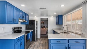 A modern kitchen with blue cabinets, stainless steel appliances, and a central island. - Charming 3-bedroom house with AC, WiFi in fabulous Glendale (Glendale)
