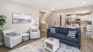 Un salon moderne avec un canapé, deux fauteuils, une table basse et un tableau accroché au mur.