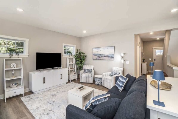 Ein modernes Wohnzimmer mit Sofa, Fernseher, weißem Schrank und einem Bild an der Wand.