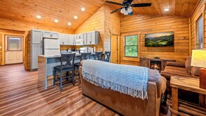 Un intérieur de chalet chaleureux comprenant un coin repas, une cuisine et une cheminée.